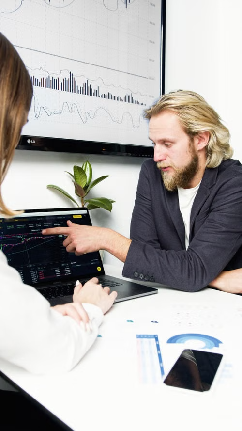 Marketing team reviewing performance charts on a laptop and display